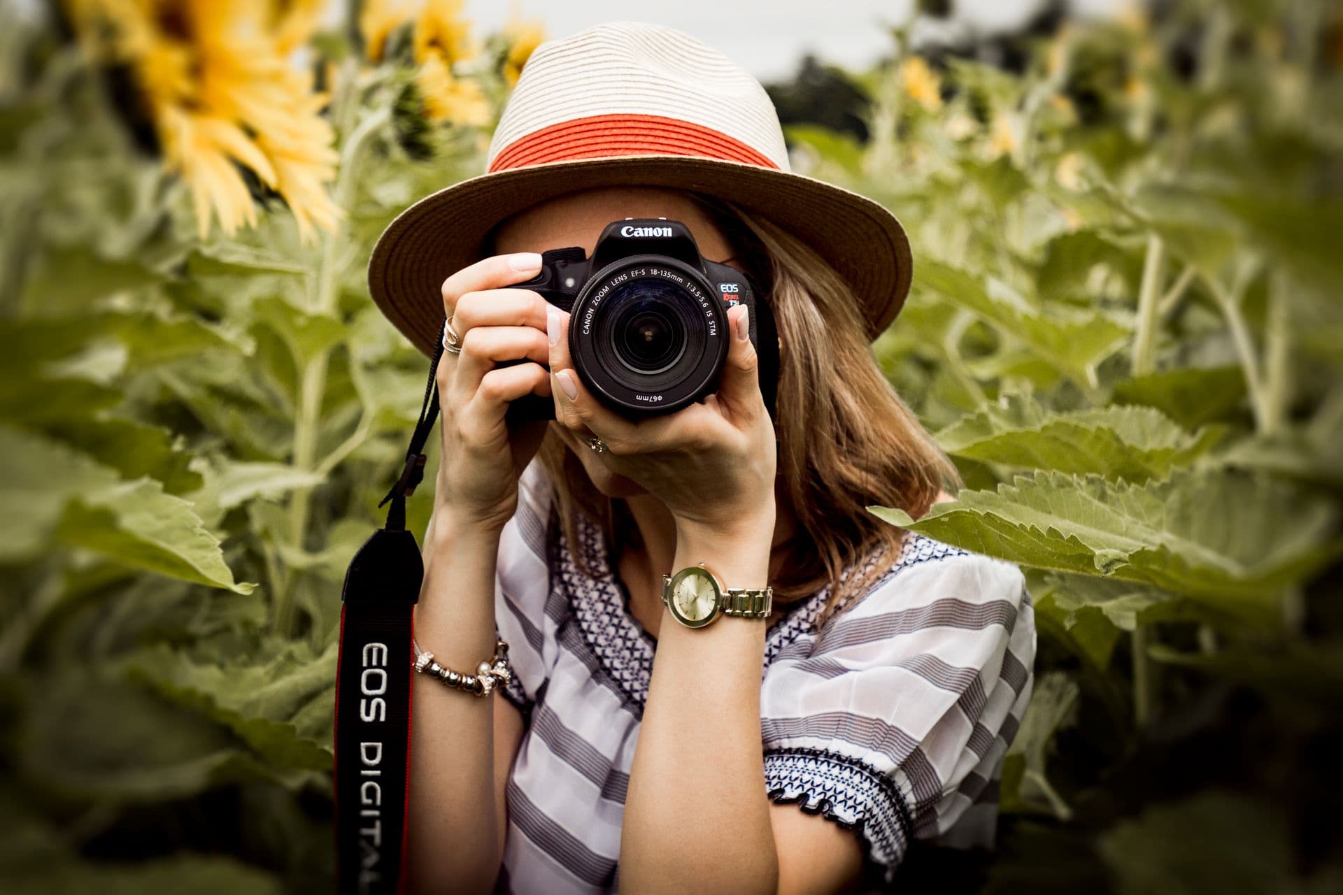 Photographer in a sun hat shooting with a DSLR