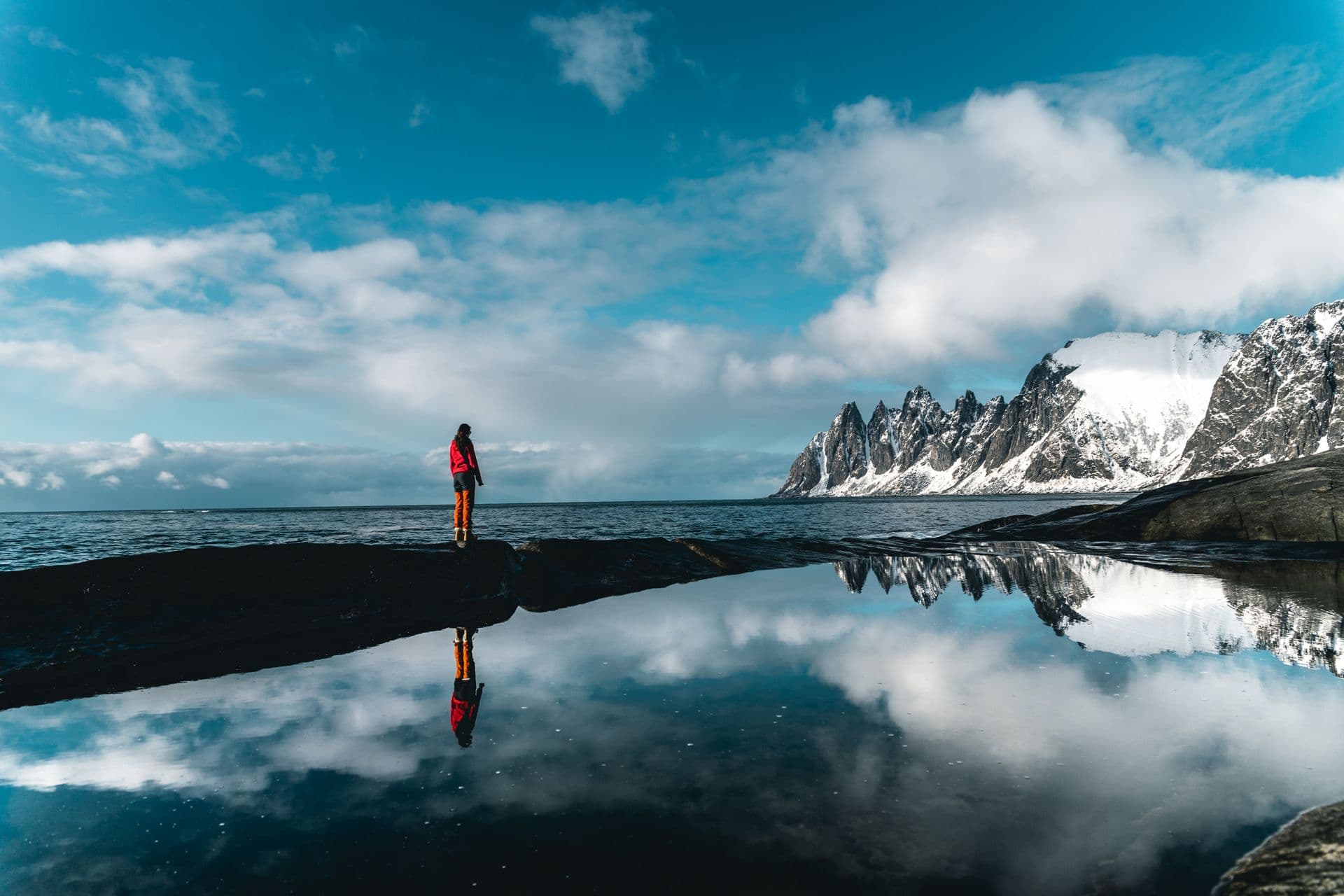 Hiker reflected in a glassy mountain lake