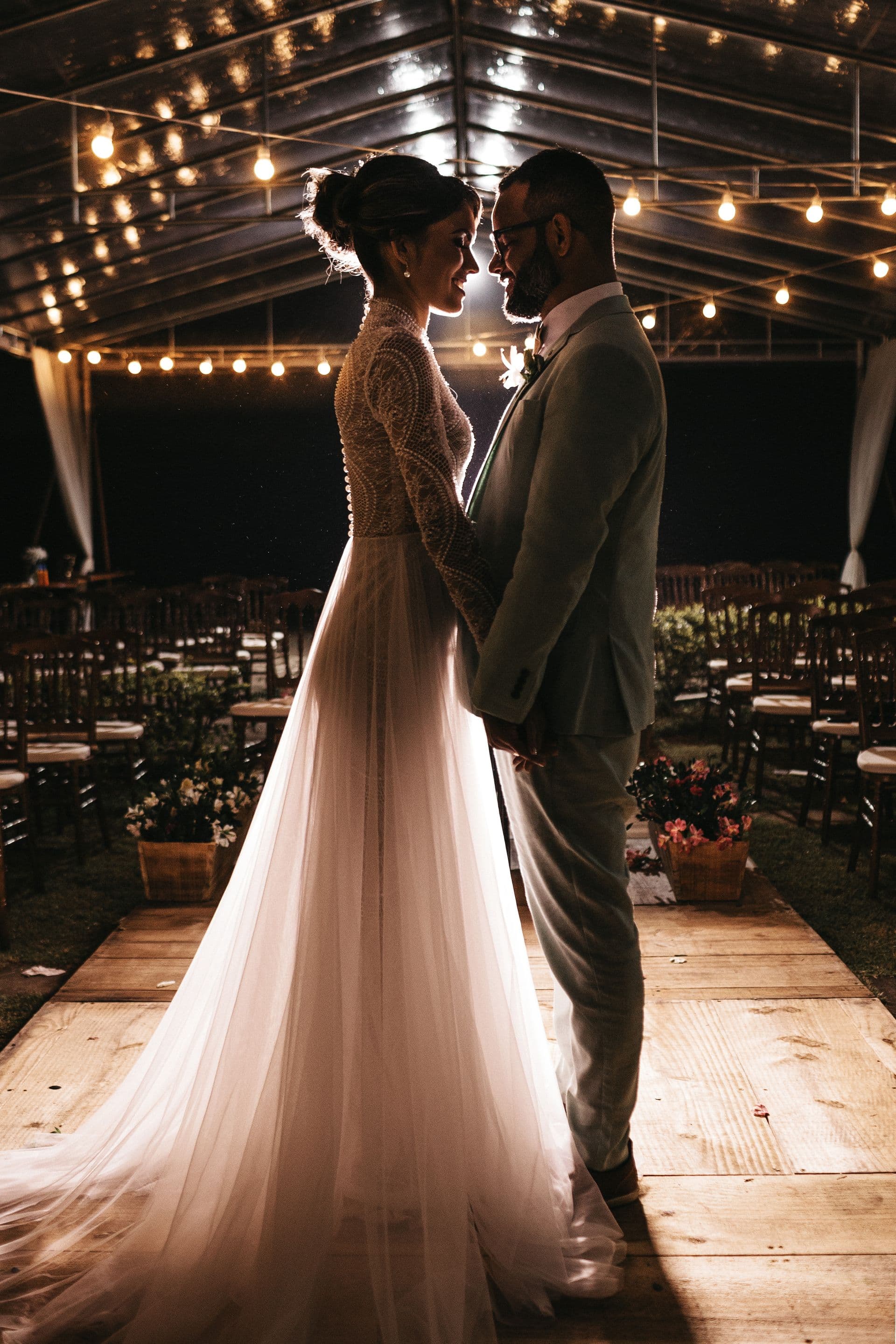 Wedding dress hanging under string lights at a venue