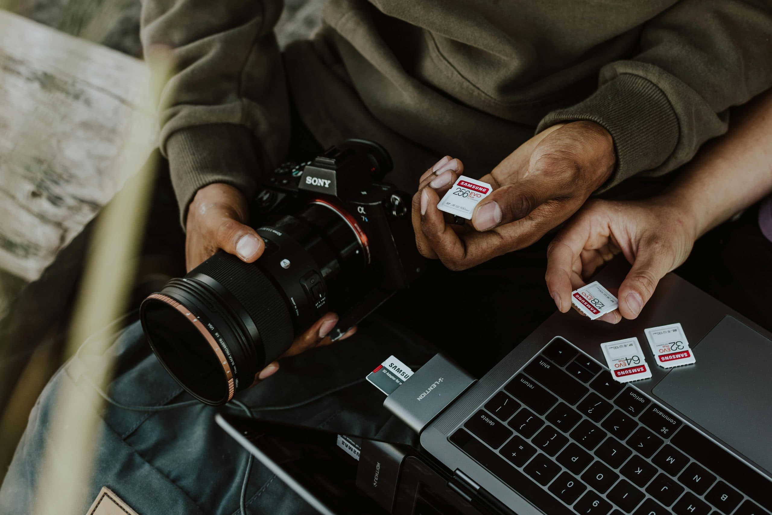 Photographer offloading SD cards into a laptop beside a camera