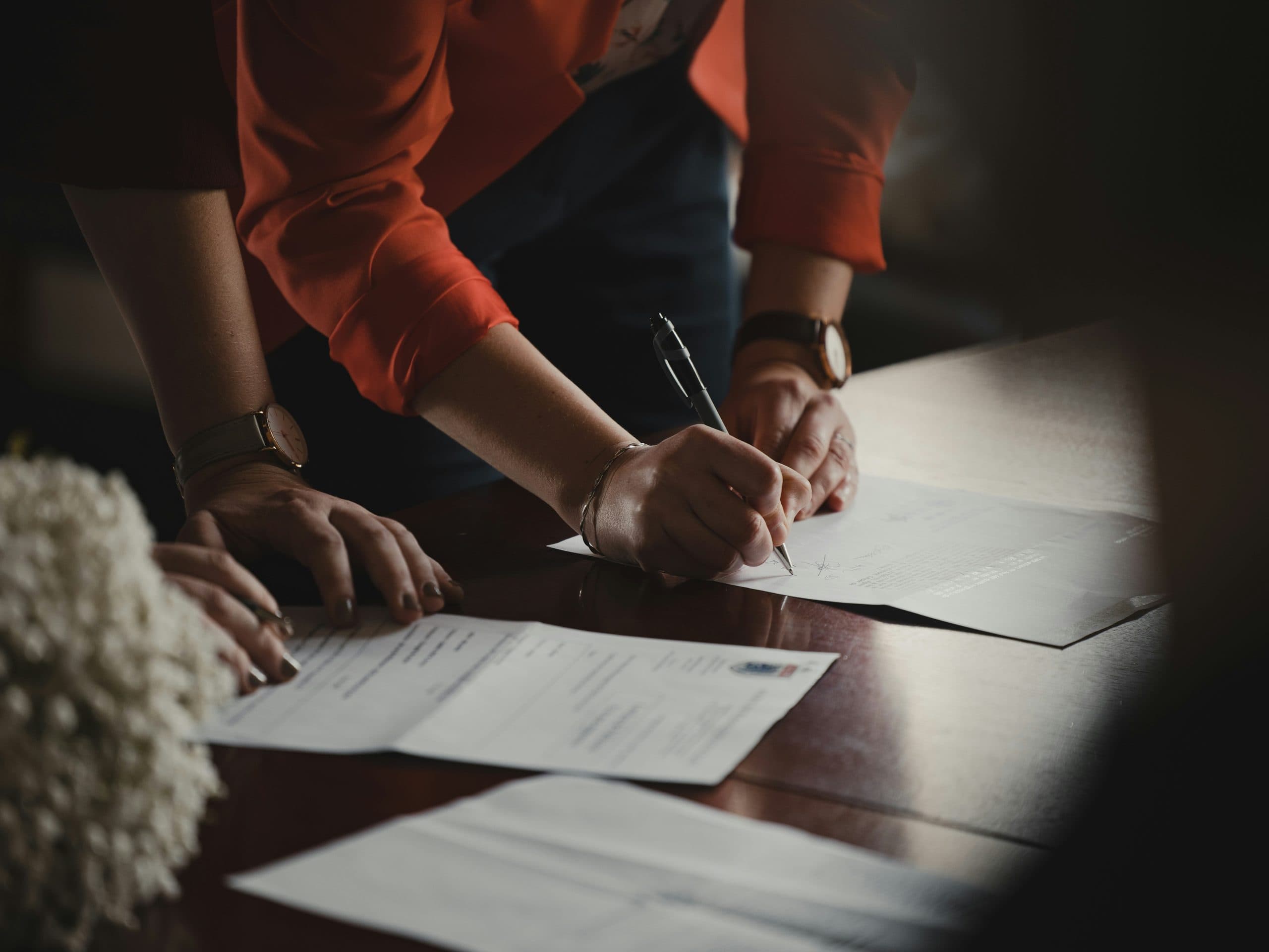 Two people signing contracts at a wooden desk