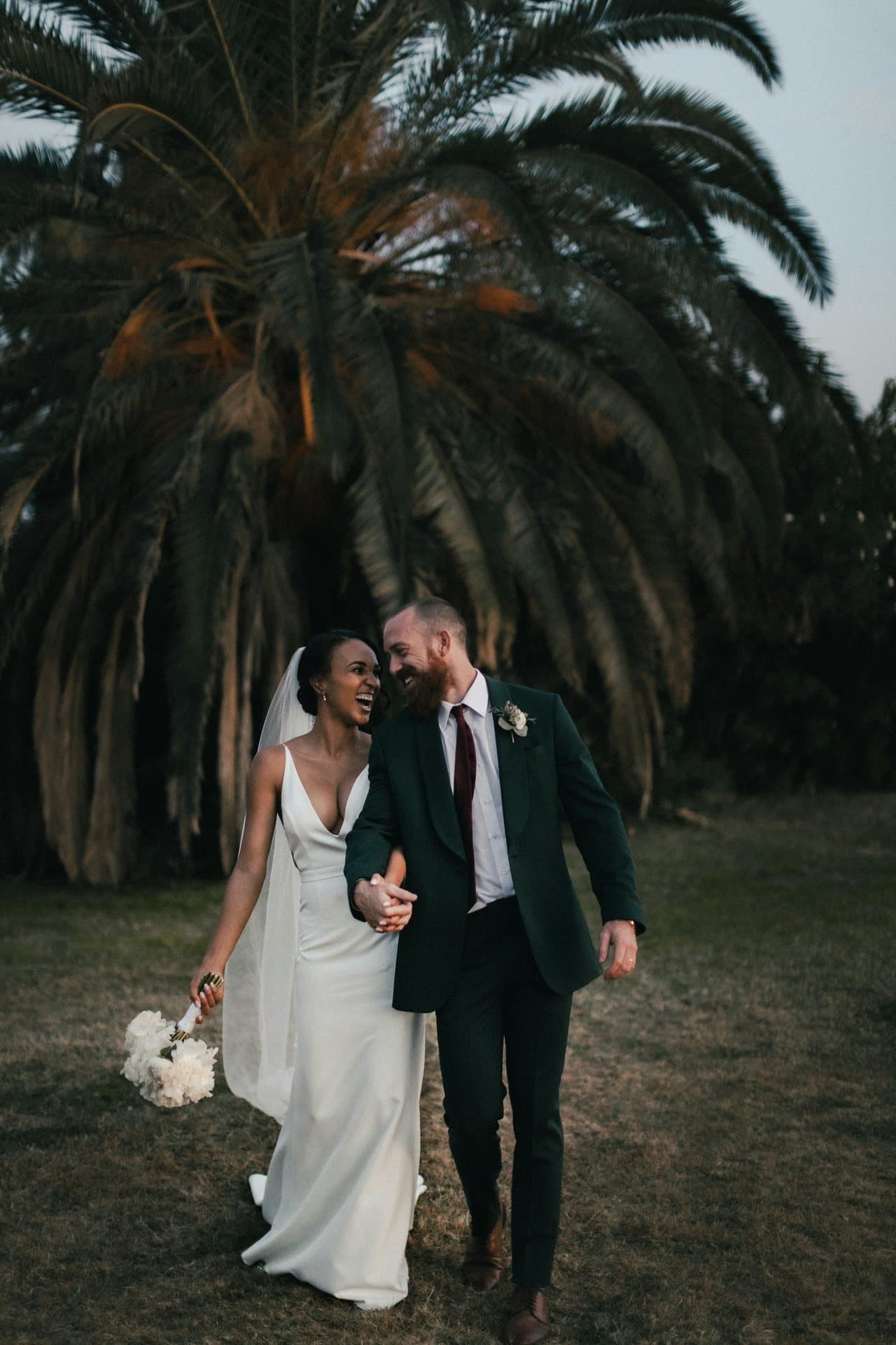 Couple on their wedding day under a palm, cinematic light